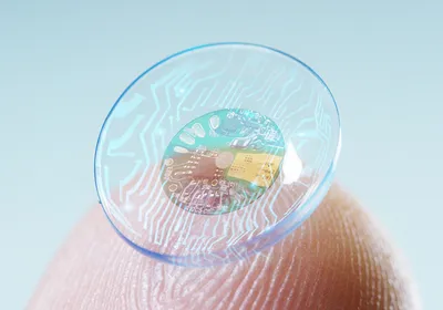 Image of macro shot of a finger holding a contact lens technology with a chip.