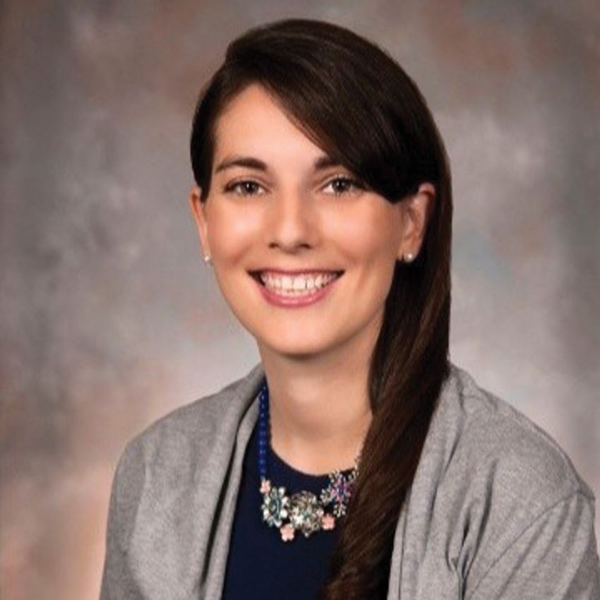 A photograph of Stephanie Servetas wearing a navy-blue top and grey jacket.
