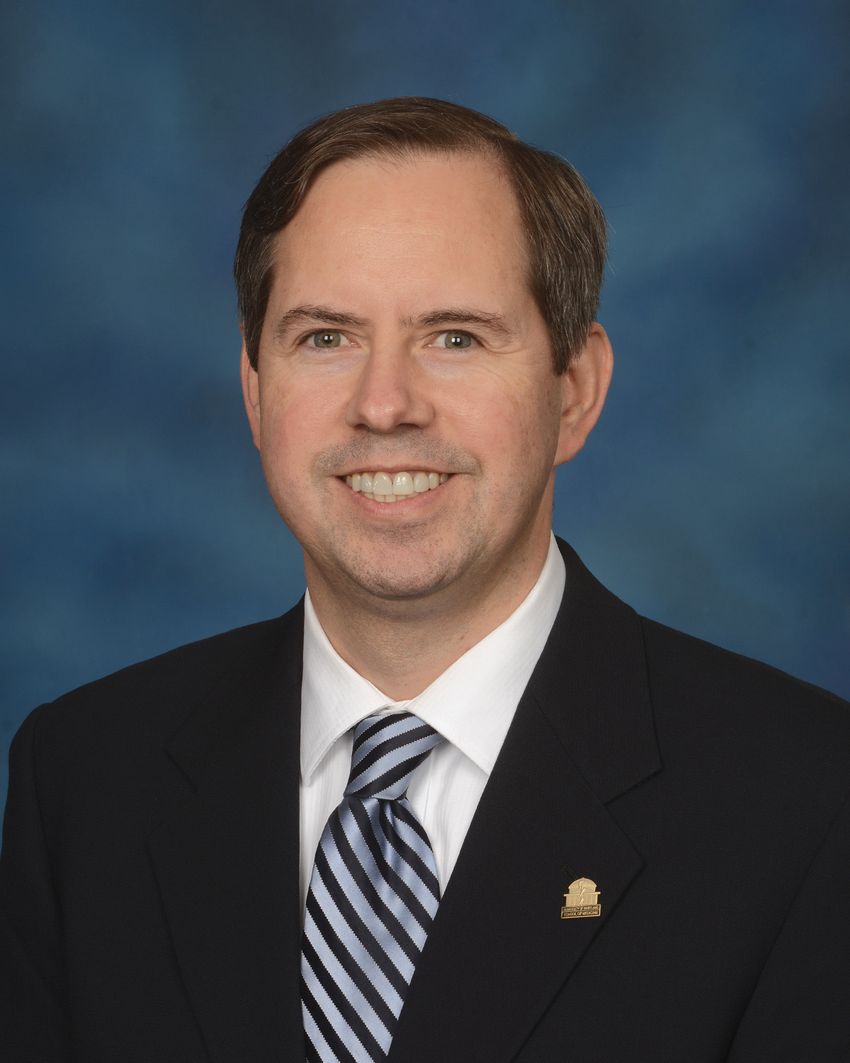 A photograph of Erik von Rosenvinge wearing a suit against a blue background.