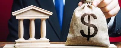 A man puts a money bag on scales opposite to building of government. Signifies NIH funding for hESC research.