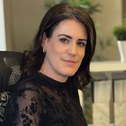 Image of Erin Lemieux sitting in a chair. She is wearing a black long-sleeved top and blue jeans.