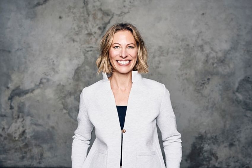 A photograph of Friederike Kleinfercher wearing a while jacket against a grey background.