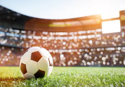 A soccer ball sits in the middle of the field in a football stadium.
