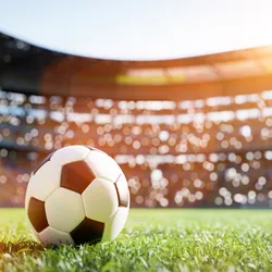 A soccer ball sits in the middle of the field in a football stadium.