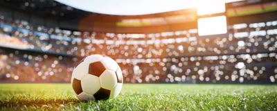 A soccer ball sits in the middle of the field in a football stadium.