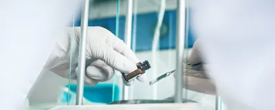 Scientist transfers a sample into a weighing vessel on an analytical balance.