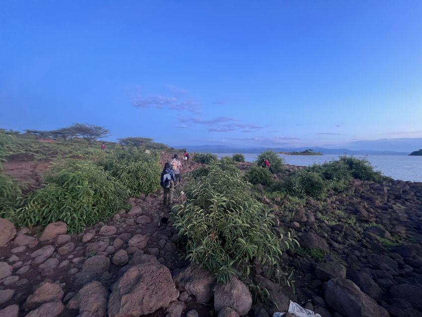 People walk on top of the dark-colored rocks with a view of the ocean on the island. People walk on top of the dark-colored rocks with a view of the ocean on the island.