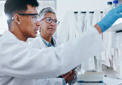 A biology student works in the laboratory under the direction of their research mentor.