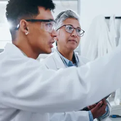A biology student works in the laboratory under the direction of their research mentor.