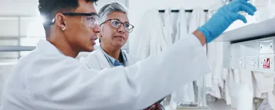 A biology student works in the laboratory under the direction of their research mentor.