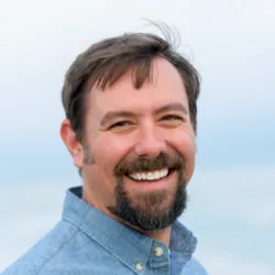 Eric Palkovacs wears a blue collared shirt and smiles in a headshot image.