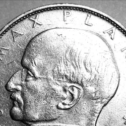 Max Planck’s profile is shown on one side of silver-colored coin.