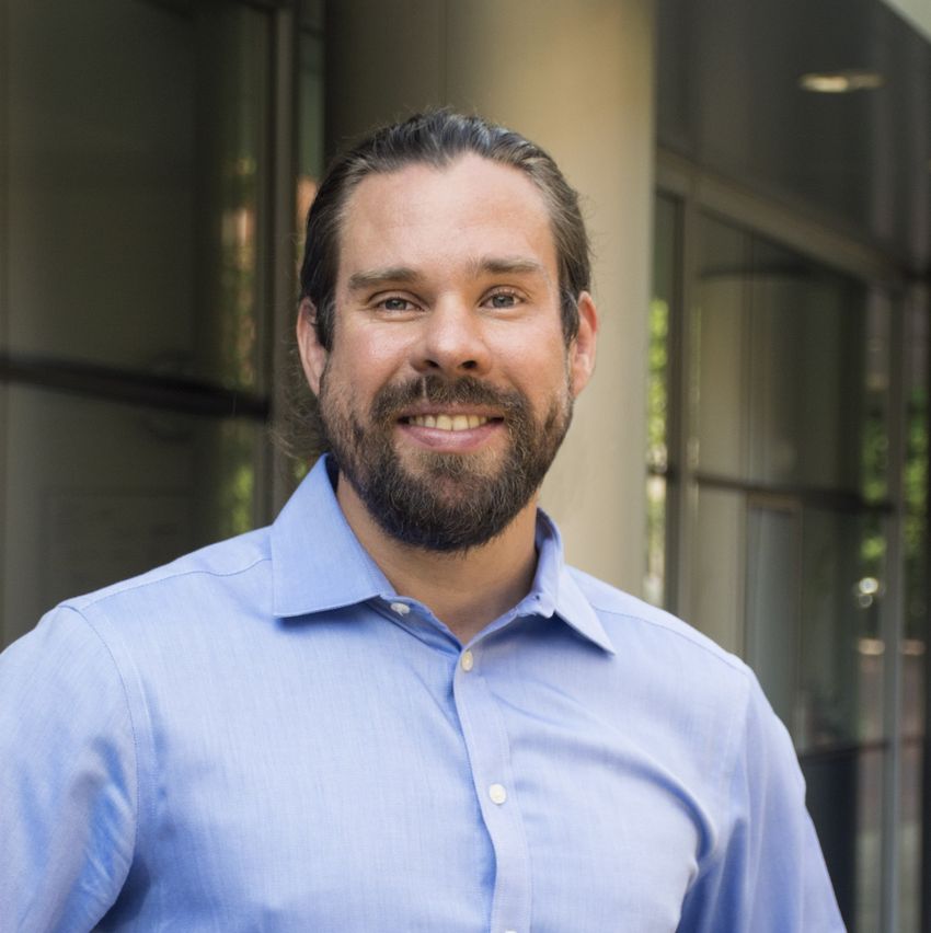 A bearded man wearing a light blue shirt.