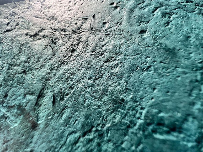A close-up photo of the teal, pitted T. rex leather. A close-up photo of the teal, pitted T. rex leather.
