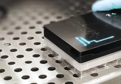A photo of a scientist placing the Resipher device on a 96-well plate.