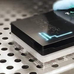 A photo of a scientist placing the Resipher device on a 96-well plate.