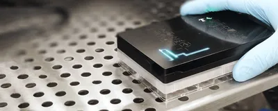 A photo of a scientist placing the Resipher device on a 96-well plate.