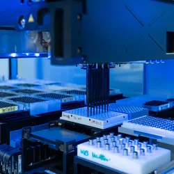 A laboratory robotics platform pipetting compounds onto a 96-well plate.