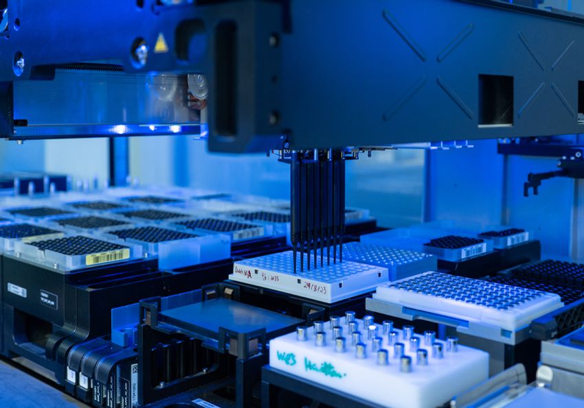 A laboratory robotics platform pipetting compounds onto a 96-well plate.