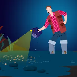 A man wearing knee-high boots stands in ankle-deep, muddy water at night, holding a wet camera. Dense brine shrimp in the shallow water obscure the thrombolites on the lakebed.