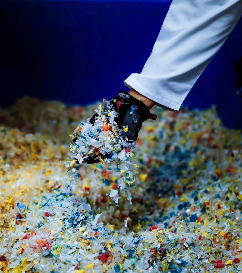 A gloved hand holds colorful plastic waste.