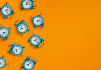 Blue alarm clocks are shown on the left side of the image against a bright orange background.