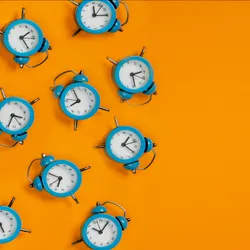 Blue alarm clocks are shown on the left side of the image against a bright orange background.