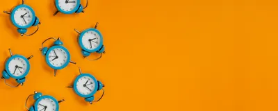 Blue alarm clocks are shown on the left side of the image against a bright orange background.