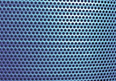 A close-up of a blue metal surface with uniform circular holes.