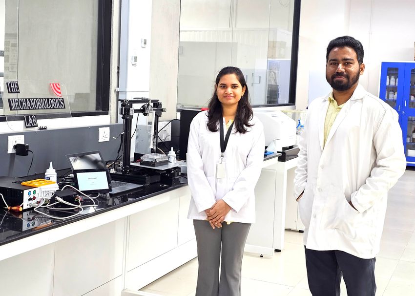 Rashmita Luha and Ajay Tijore stand in a lab wearing white lab coats.