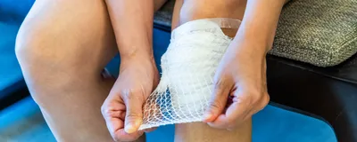 A seated person applied a bandage to their knee. 