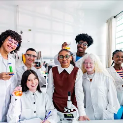 A group of diverse science students smile in a school laboratory.