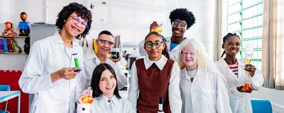 A group of diverse science students smile in a school laboratory.
