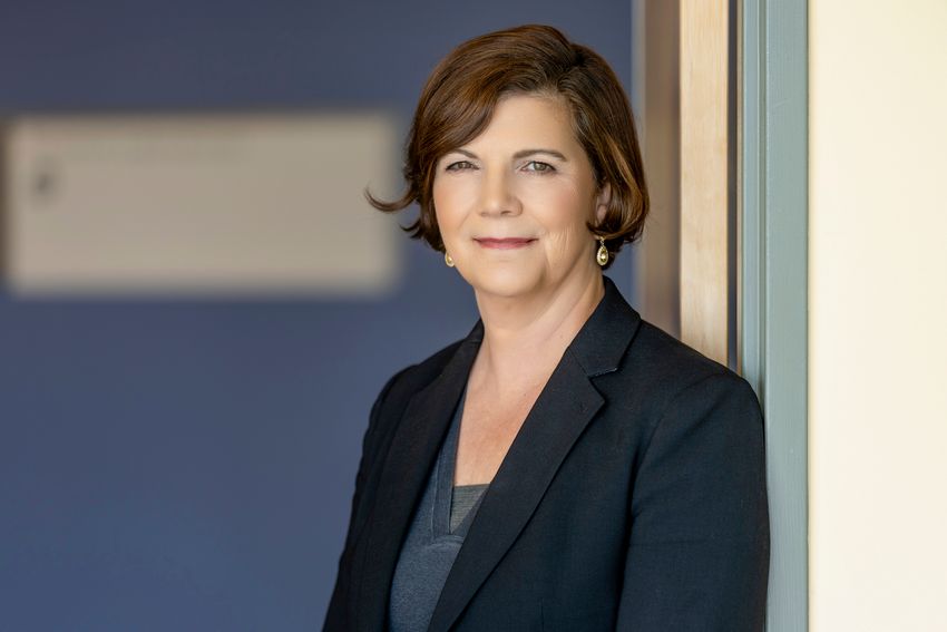 Diane Simeone wears a dark suit jacket in a headshot photo taken indoors.