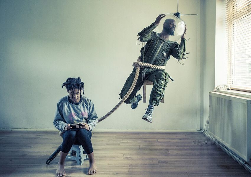 A staged photograph showing a man dressed as an astronaut who would float aimlessly away, but is tethered by a rope to a chair where a young girl sits. The photo is a personification of the man