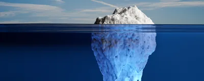 Image of a white iceberg exposing a small part out of water and hiding mostly under the ocean.