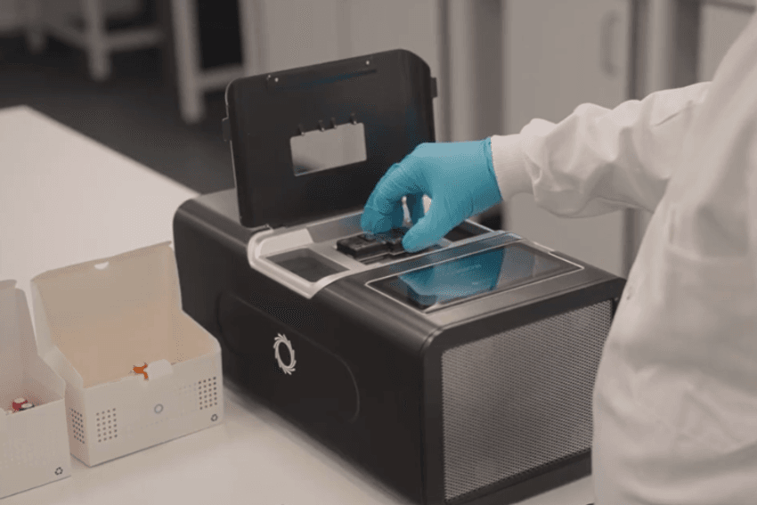 A scientist in a white lab coat and blue gloves loading a PromethION™ flow cell into a PromethION™ 2 Integrated sequencer. A scientist in a white lab coat and blue gloves loading a PromethION™ flow cell into a PromethION™ 2 Integrated sequencer.