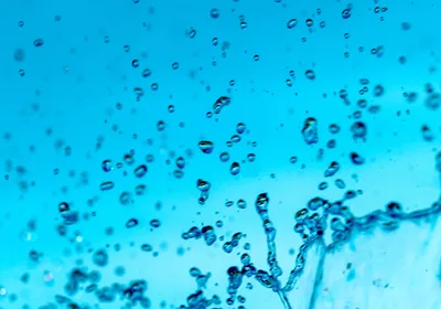 Abstract macro photography of pure water droplets and splashes suspended against a bright blue background