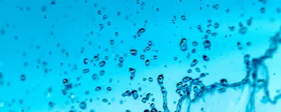 Abstract macro photography of pure water droplets and splashes suspended against a bright blue background
