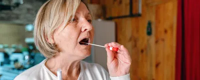 A person swabs her mouth for saliva, signifying a saliva-based age prediction test.
