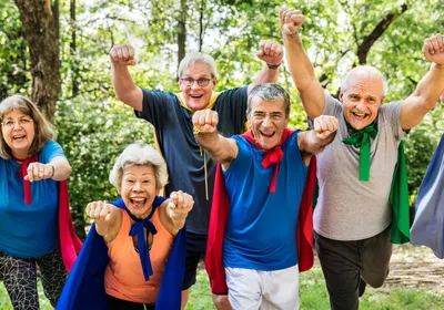 Image of a group of male and female seniors. Each person is wearing a colorful cape and looking at the camera with an excited expression.