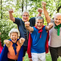 Image of a group of male and female seniors. Each person is wearing a colorful cape and looking at the camera with an excited expression.