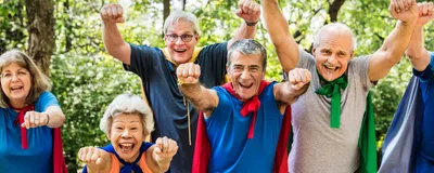 Image of a group of male and female seniors. Each person is wearing a colorful cape and looking at the camera with an excited expression.