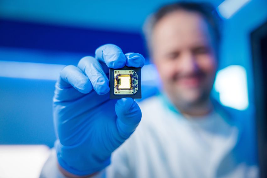 Alexander Hoischen holds a chip-like structure in his gloved hand. Alexander Hoischen holds a chip-like structure in his gloved hand.