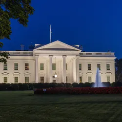 The White House is shown lit up at night.