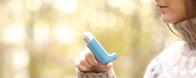 Woman hand holding asthma inhaler, signifying adult women being more prone to allergies.