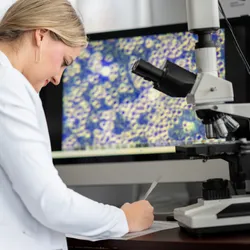 Scientist reviewing cellular and molecular data on a computer in a laboratory.