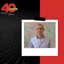 Tiago Branco wears a light blue shirt and stands in front of a white board in The Scientist’s 40th Anniversary Then and Now story template.