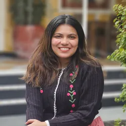 Rituparna Palit wears a dark sweater with flowers in a photo taken outside.