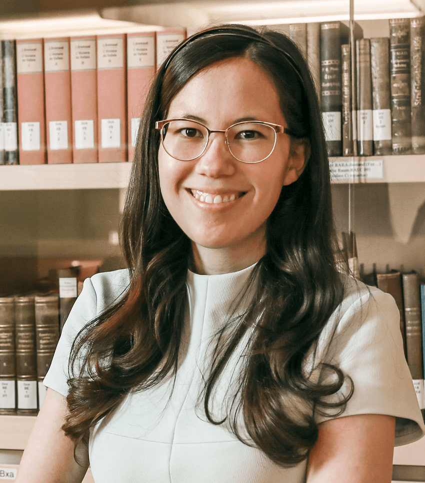 Kerstin Vokinger smiles, wearing a pale-colored shirt and glasses. Behind her are rows of shelves stacked with books. Kerstin Vokinger smiles, wearing a pale-colored shirt and glasses. Behind her are rows of shelves stacked with books.